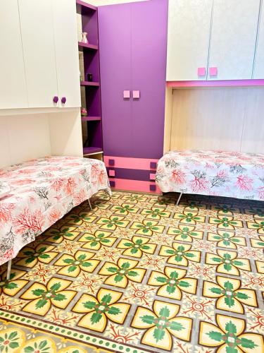 a room with two beds and a colorful floor at Casa Riccio Di Mare in Favignana