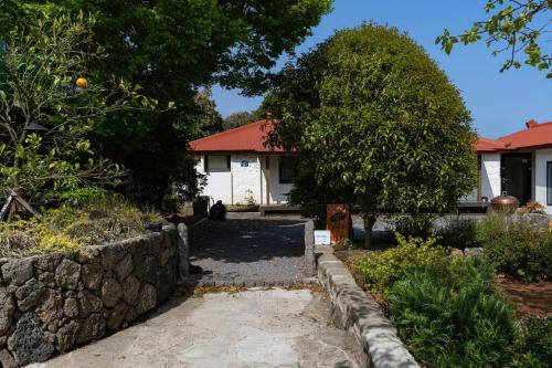 a house with a stone wall in front of a yard at HacheonBaramJip Angeori Stay Curated by Actor Ryu Seungryong in Jeju