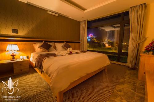 a bedroom with a large bed and a large window at Hoa Ngoc Lan - The Orchid Villa Dalat in Da Lat