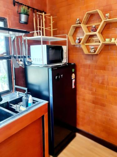 a kitchen with a microwave on top of a refrigerator at บ้านนกฮูกอิงไม้ Baannokhook in Ban Khlong Sai