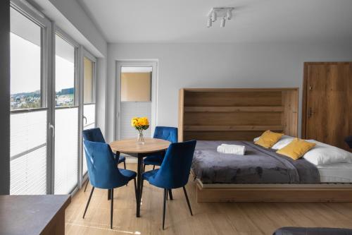 a bedroom with a bed and a table and chairs at Apartamenty Cicha - bezpłatny parking in Krynica Zdrój