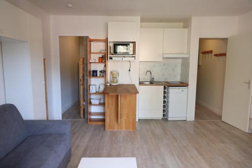 uma pequena cozinha com armários brancos e um sofá num quarto em L'Amirauté 150m de la plage em Bormes-les-Mimosas