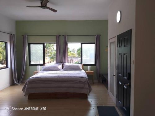 a bedroom with a large bed and two windows at Ivy Residence 4br 6ba with terrasse in Porto-Novo