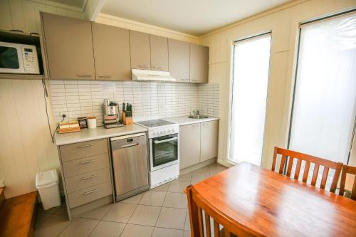 Allambie Cottages - Villa 2 في برايت: مطبخ مع طاولة خشبية ومطبخ مع طاولة وطاولة طعام