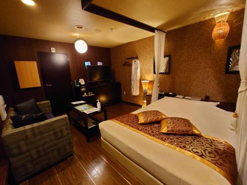 1 dormitorio con 1 cama y sala de estar en バリタイホテルアンドリゾート狭山店, en Kurosu