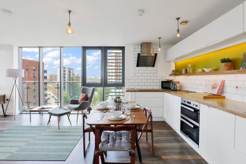 a kitchen and dining room with a table and chairs at Canary Wharf Escape - Stylish 2BR - Canal Views & City Lights in London