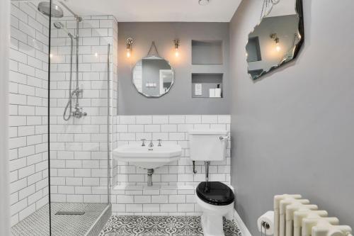 a white bathroom with a toilet and a sink at Canary Wharf Escape - Stylish 2BR - Canal Views & City Lights in London