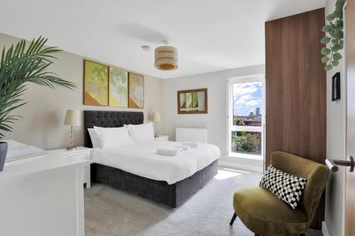 a bedroom with a bed and a chair and a window at Canary Wharf Escape - Stylish 2BR - Canal Views & City Lights in London
