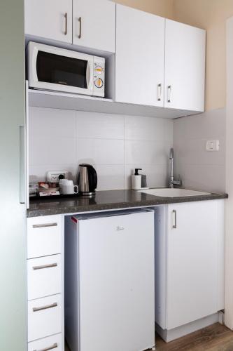 a kitchen with white cabinets and a microwave at Domus Bat Galim Hotel in Haifa