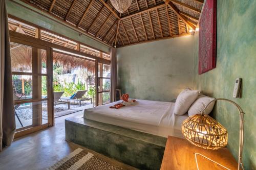 a bedroom with a bed and a table with a lamp at Villa Mandala in Gili Air