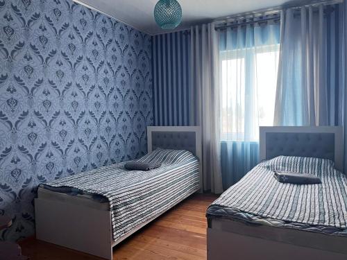 two twin beds in a bedroom with blue wallpaper at Ailus in Chok-Tal