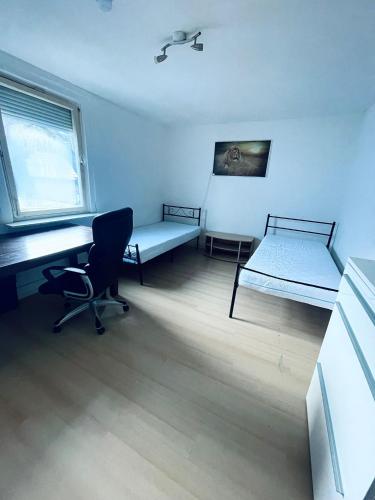 een kamer met 2 bedden, een bureau en een stoel bij Privatzimmer Staver in Weisenbach