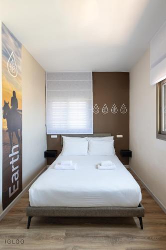 a bedroom with a large bed with white sheets at Domus Bat Galim Hotel in Haifa