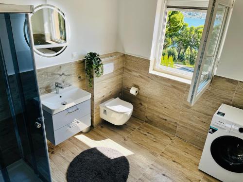 a bathroom with a sink and a toilet and a window at Apartments MIRNO MORE, Rogoznica in Rogoznica