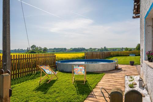 a backyard with two chairs and a pool at Ranczo Łubowice - wynajmij sobie spokój in Łubowice