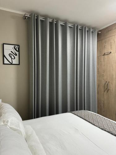 Schlafzimmer mit einem Bett und grauen Vorhängen in der Unterkunft Motswedi Place Apartments B2- Managed by Pulafela Prop Pty Ltd in Gaborone