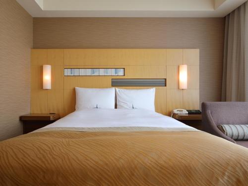 a bedroom with a large bed and a chair at Hotel Okura Fukuoka in Fukuoka