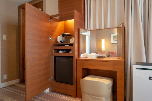 a bathroom with a vanity with a mirror and a toilet at Hotel Okura Fukuoka in Fukuoka