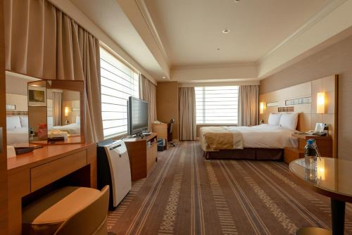 ein Hotelzimmer mit einem Bett und einem TV in der Unterkunft Hotel Okura Fukuoka in Fukuoka