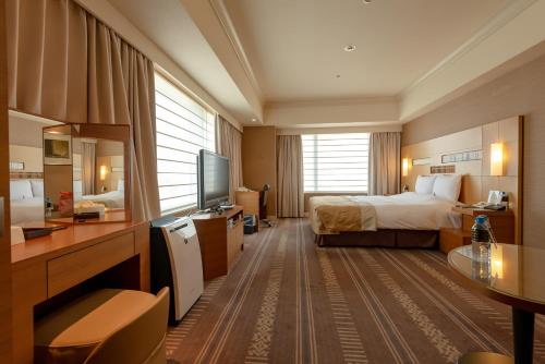 a hotel room with a bed and a television at Hotel Okura Fukuoka in Fukuoka