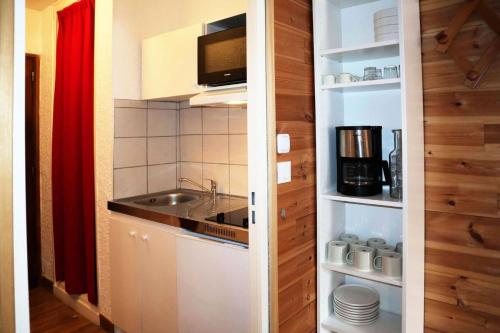 une petite cuisine avec un évier et un micro-ondes dans l'établissement Residence Le 1650 - Studio pour 4 personnes cœur de station des Orres 1650 MAE-8131, aux Orres