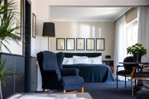 a bedroom with a bed and a blue chair at Hotel Villa Irma in Merano