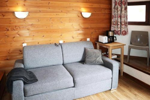 - un salon avec un canapé et un mur en bois dans l'établissement Residence Le 1650 - Studio pour 4 personnes cœur de station MAE-8161, aux Orres