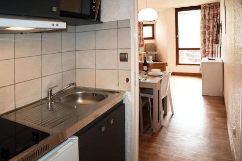 une petite cuisine avec un évier et une table dans l'établissement Residence Le 1650 - Studio pour 4 personnes cœur de station MAE-8161, aux Orres