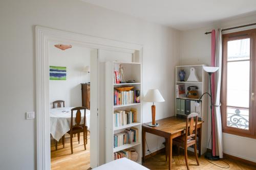 Cette chambre comprend un bureau et une étagère avec des livres. dans l'établissement Harmonie Intemporelle, à Paris