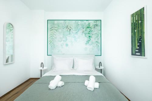 a bed with white pillows and a painting on the wall at Fina Apartment in Opatija