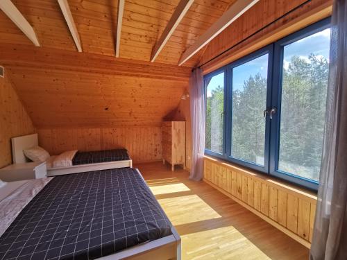 a room with two beds in a room with windows at Leśne Wspomnienia in Niesiołowice