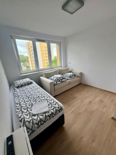 1 dormitorio con cama y sofá en Pokoje Brynów, en Katowice