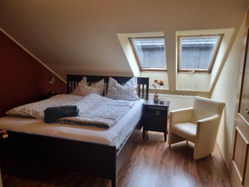 a bedroom with a bed and a chair and two windows at Lindengut Natternbach in Natternbach