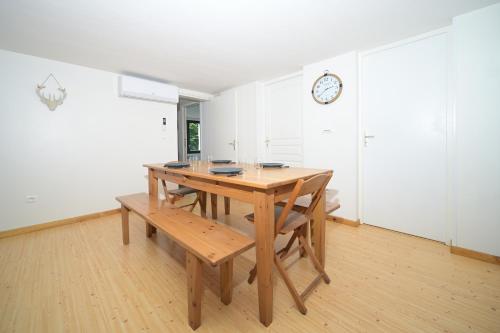 a wooden table and bench in a room with a clock at Chalet Appartement Les Isards in Saint-Lary-Soulan