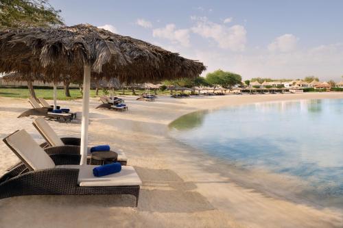 a beach with chairs and an umbrella and water at InterContinental Al Jubail Resort by IHG in Al Jubail