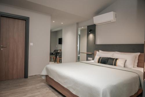 a bedroom with a large white bed and a kitchen at Elizabeth Queen Luxury Rooms in Paralia Katerinis