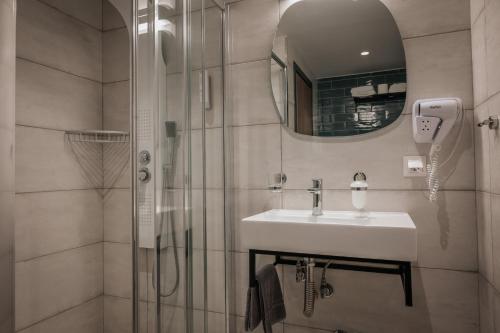 a bathroom with a sink and a shower with a mirror at Elizabeth Queen Luxury Rooms in Paralia Katerinis