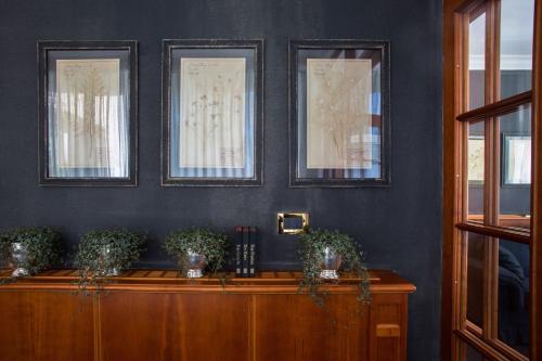a room with three pictures on the wall and a table with plants at Hotel Villa Irma in Merano