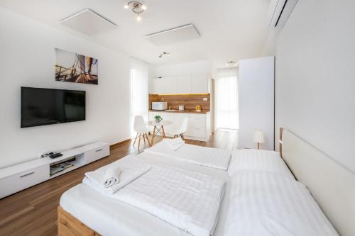 ein weißes Schlafzimmer mit einem großen Bett und einem Flachbild-TV in der Unterkunft Anchor Apartman by HelloBalatonlelle in Balatonlelle