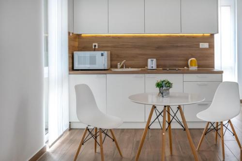 a kitchen with white cabinets and a table and chairs at Anchor Apartman by HelloBalatonlelle in Balatonlelle