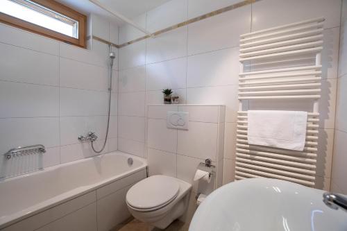 a white bathroom with a toilet and a tub and a sink at Haus Bella Vista in Riederalp