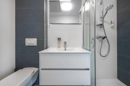 a bathroom with a white sink and a shower at Anchor Apartman by HelloBalatonlelle in Balatonlelle
