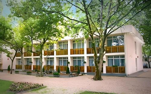 un bâtiment avec des arbres devant lui dans l'établissement PSZ Hotel Beach Földvár, à Balatonföldvár
