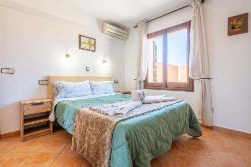 een slaapkamer met een bed met een groene deken en een raam bij Capricho in Portocolom