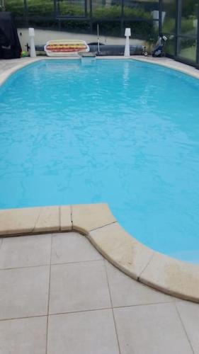 une grande piscine avec de l'eau bleue dans un immeuble dans l'établissement Belle Chaumière Normande, au pas de la ville d'Honfleur, à Conteville