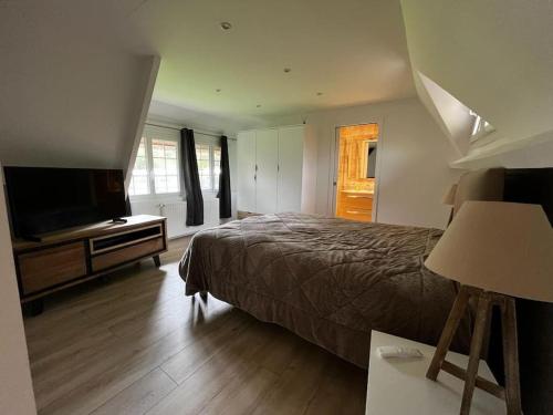 une chambre avec un lit et une télévision à écran plat dans l'établissement Belle Chaumière Normande, au pas de la ville d'Honfleur, à Conteville