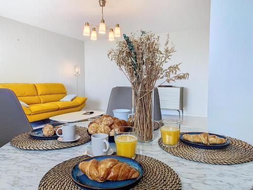 - une table avec deux assiettes de croissants et de jus d'orange dans l'établissement Horizon bleu vue mer dernier étage clim, à Saint-Laurent-du-Var