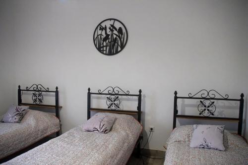 a bedroom with two beds and a clock on the wall at Réti Tanya Vendégház in Kerecseny