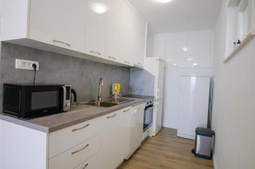 a kitchen with white cabinets and a sink and a microwave at Lemon tree in Podaca