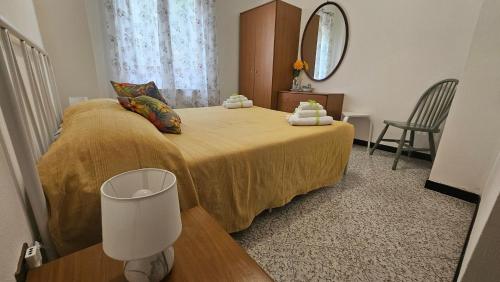 a bedroom with a bed with a yellow blanket and a mirror at La valle fiorita in Soviore